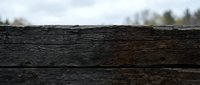 Weathered wooden planks with natural aging and texture against blurred outdoor background for rustic design projects and natural material concepts.