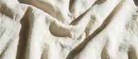 Crumpled beige linen fabric with natural texture and soft shadows, suitable for backgrounds, textile design, and interior styling projects.