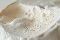 White soap foam with bubbles in macro photography showing delicate texture and light patterns, suitable for hygiene and cleanliness concepts.