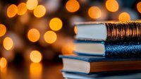 Stack of books with blue and copper textured covers against warm golden bokeh lights, suitable for education, learning, library, and academic design projects.