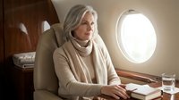 Elegant senior Caucasian businesswoman in beige attire relaxing in luxury private jet cabin during flight, representing premium travel and success.