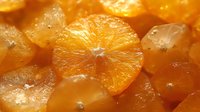 Fresh orange slices with water drops on glossy surface, vibrant citrus fruit close-up macro photography in warm golden light, healthy food background.