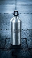 Metallic water bottle with black cap sitting on asphalt pavement, suitable for beverage, lifestyle, and product marketing campaigns.