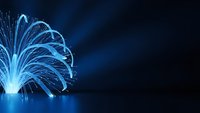 Blue fiber optic cables creating fountain-like light streams on dark background for technology and communication concepts.