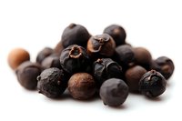 Dried juniper berries scattered on white background, macro food photography with selective focus. Essential ingredient for gin production and cooking.