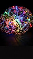 Tangled wire ball with colorful LED lights creating magical glow on dark surface for holiday decoration and festive lighting concepts.