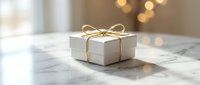 White gift box with elegant gold ribbon bow on marble surface, soft bokeh background, luxury holiday present concept.