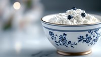 Fresh cottage cheese with blueberries served in traditional porcelain bowl with blue floral pattern. Soft focus morning light creates cozy breakfast atmosphere.