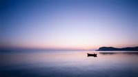 Serene twilight seascape with lone fishing boat on calm waters at dusk, purple and pink sky reflecting on peaceful ocean surface for meditation and relaxation.