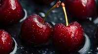 Fresh ripe cherries with water droplets on dark surface, ideal for food and beverage design projects.