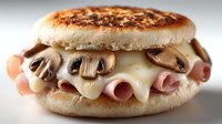 Gourmet English muffin sandwich with melted cheese, sliced ham, and sauteed mushrooms on white background isolated for culinary design projects.