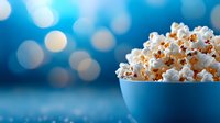 Fresh popcorn in blue bowl against blurred bokeh background with soft lighting creates cozy movie night atmosphere. Perfect for entertainment concepts.