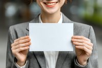 Smiling businesswoman in gray suit holding blank white card, perfect for adding custom message or company information.