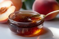 Golden honey dripping from spoon into glass bowl with fresh peaches in background, macro food photography showing transparent amber sweetness.