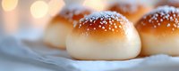 Fresh baked sweet buns with sesame seeds on top, close up view showing golden brown crust and soft texture against blurred bokeh background.