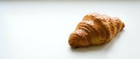 Fresh golden croissant with flaky layers isolated on white background for bakery menu design and food photography projects.
