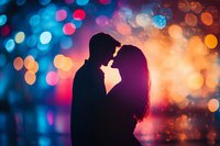 Romantic silhouette of couple about to kiss against vibrant bokeh background with blue and orange lights creating dreamy atmosphere for Valentine's day cards and dating apps.