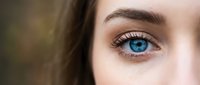 Close-up of young Caucasian woman's striking blue eye with natural makeup and long eyelashes for beauty and skincare concepts.