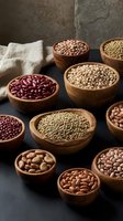 Assorted legumes and beans in wooden bowls on dark surface with rustic background for healthy cooking and nutrition concepts.