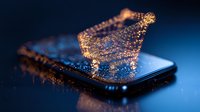 Glowing butterfly silhouette emerging from smartphone screen with sparkles and magical light effects against dark blue background, digital transformation concept.