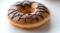 Spider web design on glazed donut with chocolate icing decoration creating spooky Halloween treat on white background, macro food photography.