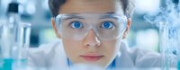 Young female scientist wearing protective goggles in modern laboratory setting with research equipment and glassware, close up portrait with bright blue eyes.