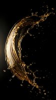 Golden liquid splash forming curved wave with droplets on black background for beverage advertising and product photography.