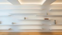 Modern white floating shelves on wall with warm lighting and wooden floor for contemporary interior design and home decor display storage solutions.