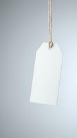 Blank white paper price tag hanging on natural rope string against neutral gray background for retail labeling and product identification.