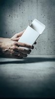 Male hands holding blank white cigarette pack mockup against concrete wall background for tobacco product branding and packaging design presentation.