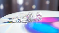 Sparkling diamonds and gemstones creating rainbow light reflections on white surface with bokeh background for luxury jewelry advertising.
