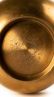 Antique brass bowl with engraved calligraphy details, warm golden patina, aged metal texture, handcrafted vintage decor for interior and cultural design projects.