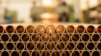 Stacked bamboo tubes arranged in rows creating geometric pattern with warm lighting and blurred background for sustainable construction materials.