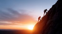 Two climbers ascending steep rocky cliff face during golden hour sunset with dramatic orange and purple sky backdrop for adventure and outdoor recreation concepts.