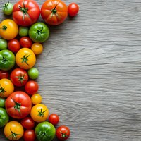 Fresh colorful tomatoes arranged on rustic wooden background with copy space for text. Organic heirloom varieties in red, yellow and green colors for cooking.
