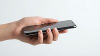Female hand holding modern black smartphone with protective gesture on white background isolated for technology and communication concepts.