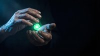 Hands holding glowing green energy orb against dark background, representing power, magic, healing, technology, and innovation for creative projects.
