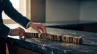 Businessman hands arranging wooden letter blocks spelling small business grant on marble desk surface in modern office environment for funding concept.