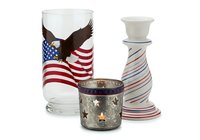 Patriotic glassware set featuring eagle and flag design on drinking glass, decorative candle holder with striped pattern, and star-embellished votive holder for home decor.