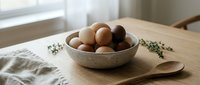 Fresh brown eggs in ceramic bowl on wooden cutting board with herbs creating rustic kitchen scene for cooking and baking projects.