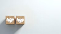 Business partnership concept with wooden blocks showing handshake icons on white background for corporate agreements and teamwork presentations.