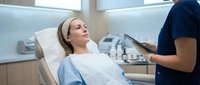 Young Caucasian woman patient relaxing in modern dental chair during routine checkup with healthcare professional in bright clinical setting.
