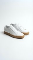 White leather low-top sneakers with gum rubber sole, isolated on light background. Minimalist unisex casual footwear for fashion, retail, and lifestyle use.