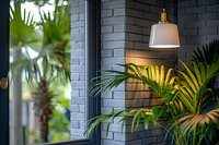 Modern interior design with white pendant lamp against gray brick wall, featuring lush tropical palm leaves creating cozy atmospheric lighting perfect for home or restaurant decor.