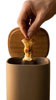 Hand dropping an apple core into a stylish ceramic compost bin with bamboo lid, promoting sustainable living and zero waste lifestyle.
