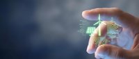 Hand holding glowing digital microchip with circuit board patterns and light effects against blurred background. Technology and innovation concept.