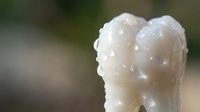White foam or soap bubbles forming dense clusters with natural outdoor background blur for cleaning and hygiene concepts.