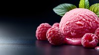 Fresh raspberry ice cream scoop with whole berries and mint leaves on dark background with water drops, selective focus and copy space for dessert menu.