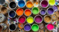 Colorful paint cans with vibrant acrylic paints in rainbow colors arranged on artist workspace. Creative art supplies for painting projects and artistic expression.