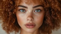 Close-up portrait of young woman with curly red hair, blue eyes, and freckles against neutral background, perfect for beauty and skincare advertising.